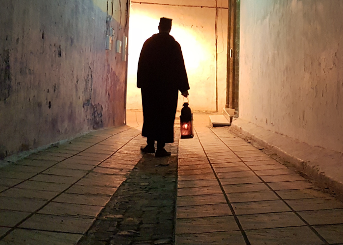 A middle eastern man walking with a lantern