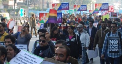 Crowd of people carrying rainbow signs at a protest in India