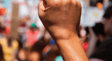 Image of a fist in the air at a protest against a blurred backrgoundblure