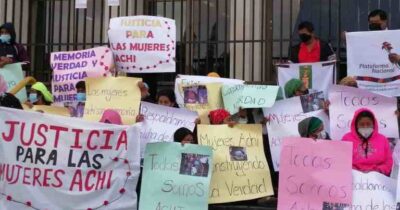 Indigenous women outside of Guatemala's highest court holding handmade signs
