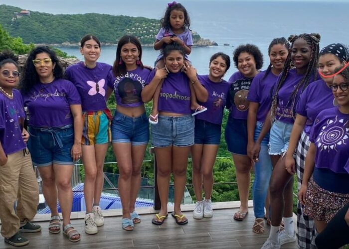 group of young women posing for photo near water