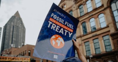 person holding poster that states "It's time for a Fossil Fuel Non-Proliferation Treaty"