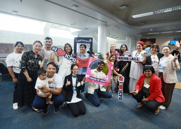 Group of people smile and hold up signs in support of ICPD