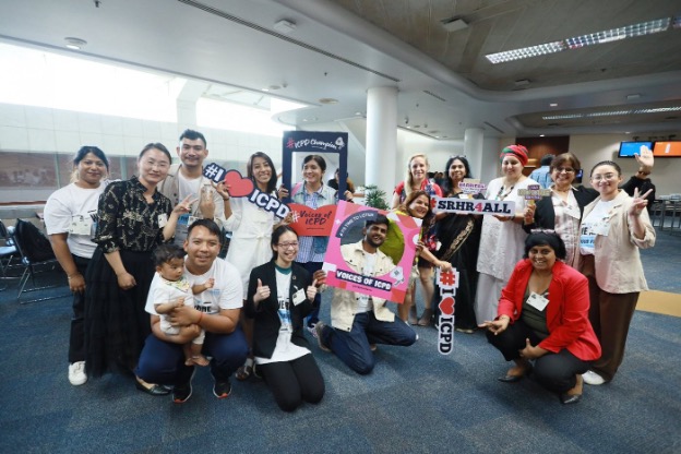 Group of people smile and hold up signs in support of ICPD