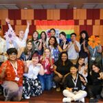 Workshop attendees stand in front of Pride flag