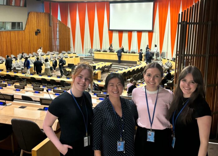 Attendees smile in front of conference room.