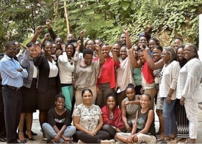Smiling group of people outside, many raising fist in solidarity.