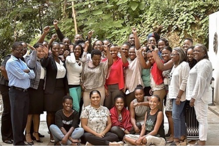 Smiling group of people outside, many standing and raising fist.