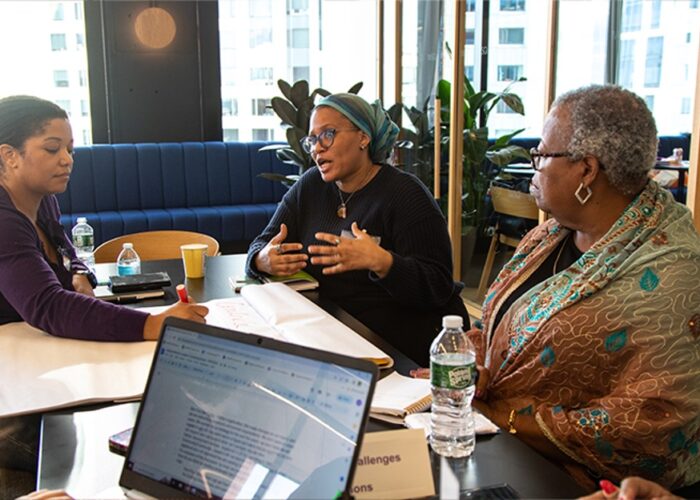 Three women converse in conference room