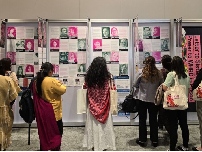 Women stand in front of a display on women human rights defenders.