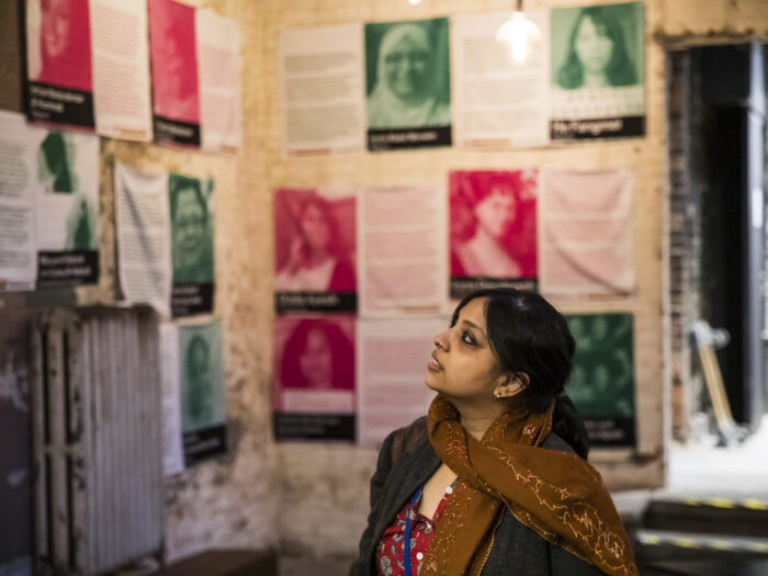 Women looks up at wall of women human rights defenders photographs and bios