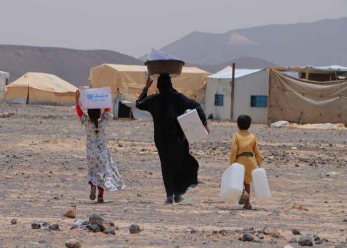 Woman and children carry food and aid to camps