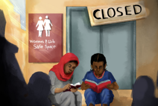 Two young girls sit in front of what was formerly the Women & Girls Safe Space but now closed.