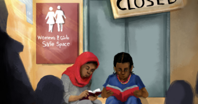 Two young girls sit in front of what was formerly the Women & Girls Safe Space but now closed.